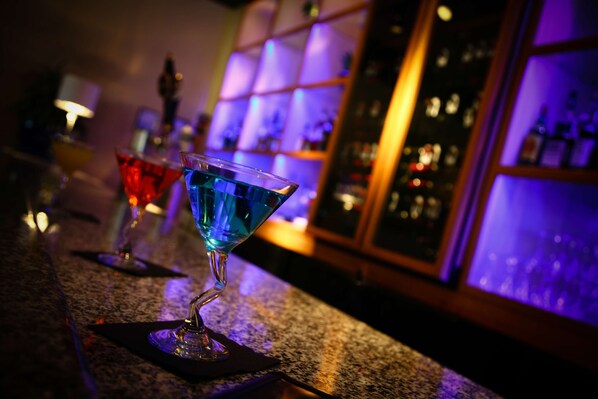 A bar area with a granite countertop, a blue cocktail glass, and a red cocktail glass.