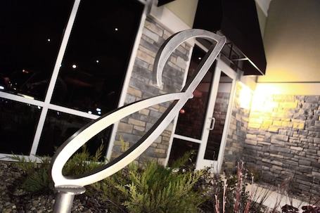 A metal sculpture in front of a building with a stone facade and a glass door.