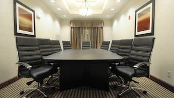 Una sala conferenze con un tavolo rotondo e sei sedie in pelle nera dotate di rotelle.