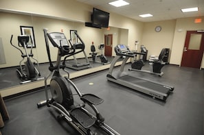 A fitness center with various cardio machines, a large mirror, and a clock on the wall. - Holiday Inn Express Somerset by IHG (Somerset)