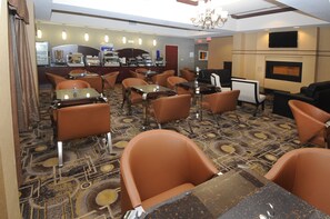 A hotel dining area with multiple tables and chairs, a coffee station, and a television screen. - Holiday Inn Express Somerset by IHG (Somerset)