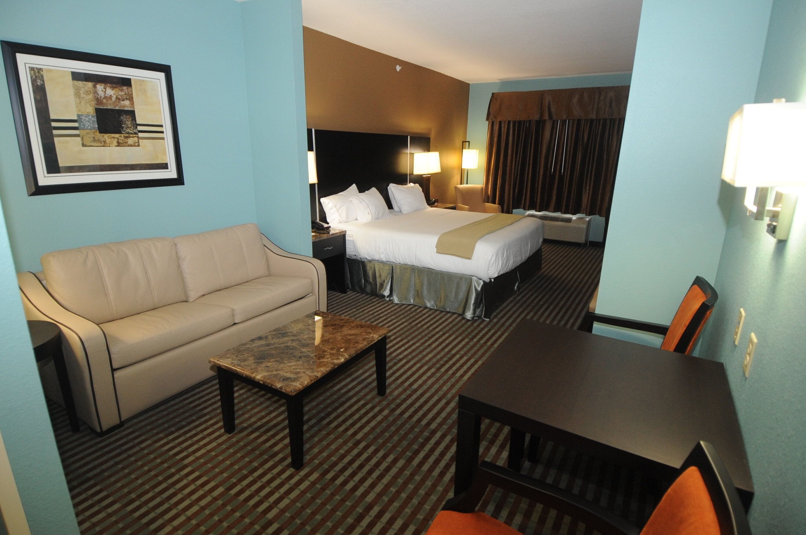 Habitación de hotel con cama, sofá, mesita de centro, escritorio y silla.
