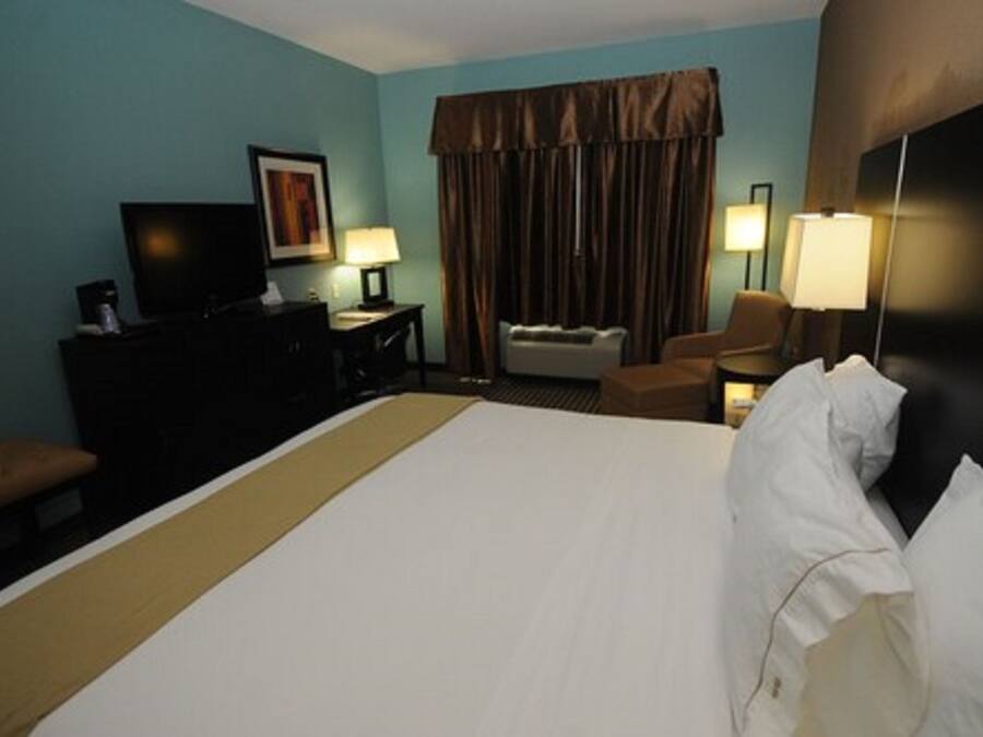 A hotel room with a large bed, a desk with a computer, a chair, and two lamps.