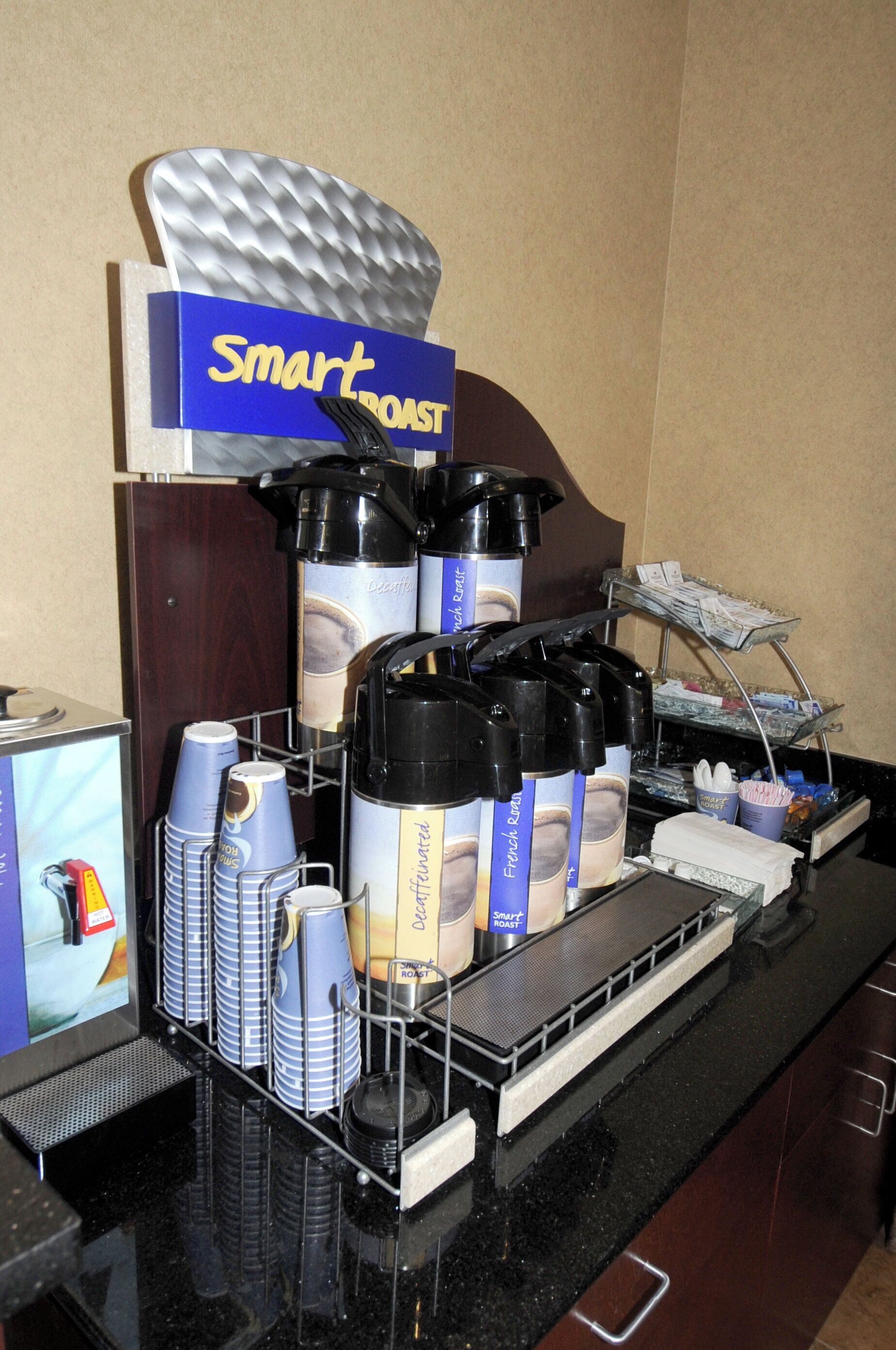 Una estación de café con varios dispensadores, tazas y un letrero que dice 'Smart Roast'.
