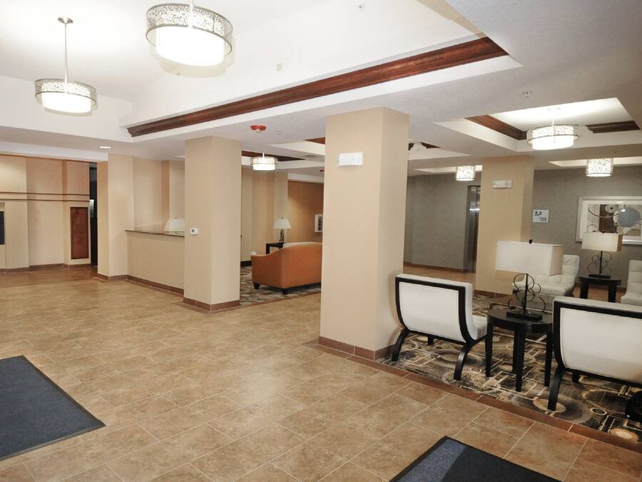 A hotel lobby with a reception desk, seating area, and a kitchenette.
