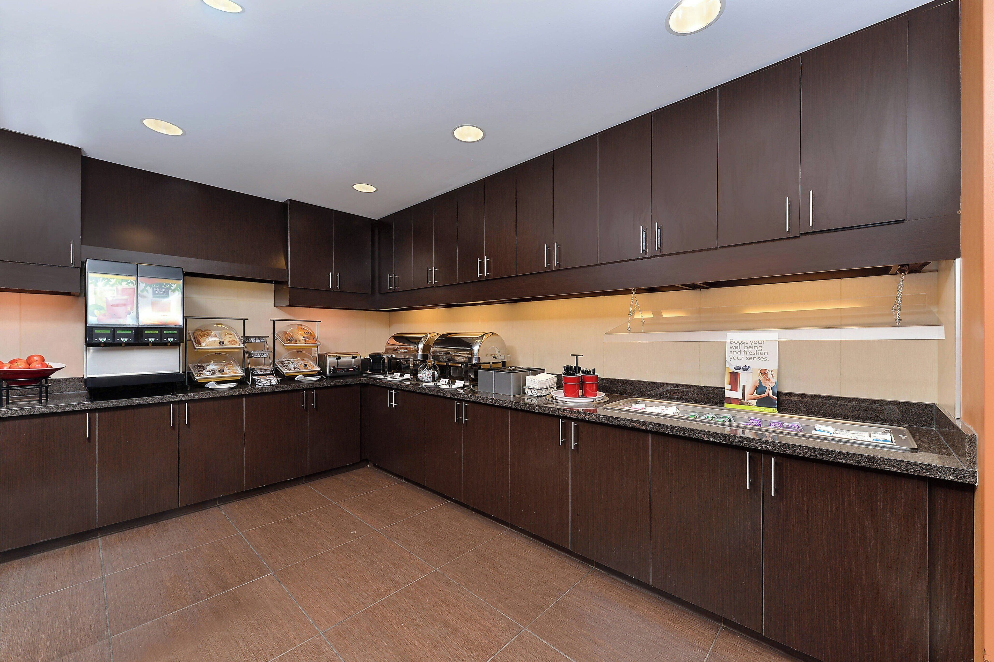 Una cocina moderna con armarios de madera oscura, encimera de granito y varios electrodomésticos, incluyendo una cafetera y un tostador.