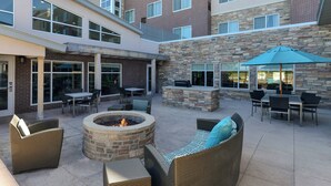 An outdoor patio with wicker furniture, a fire pit, and a stone wall. - Residence Inn by Marriott Coralville (Coralville)