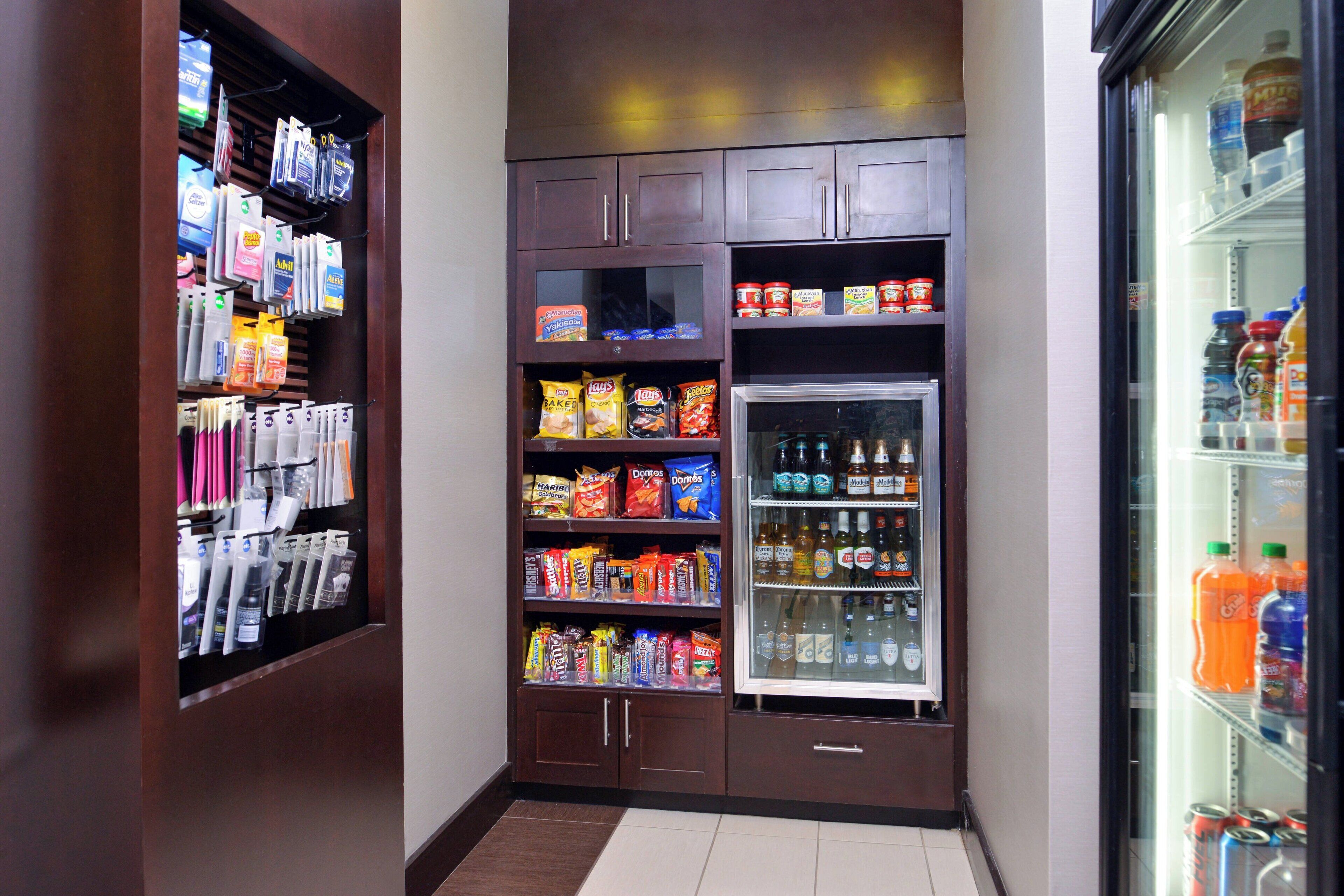 A small, well-organized snack and beverage area with shelves stocked with various snacks, chips, and bottled drinks.
