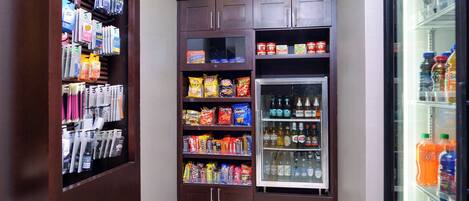 A small, well-organized snack and beverage area with shelves stocked with various snacks, chips, and bottled drinks.