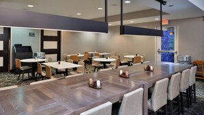 Een vergaderzaal met een lange tafel, meerdere stoelen en een klein kitchenette.