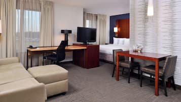 Une chambre d’hôtel comprenant un lit, un bureau avec une télévision, une table à manger avec des chaises et un canapé.
