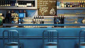 A bar area with multiple shelves of wine bottles, a chalkboard with breakfast suggestions, and bar stools.