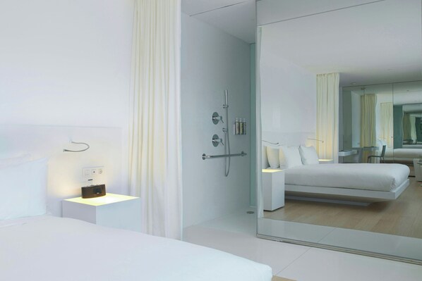 A modern hotel room with a large bed, bedside table, and a glass shower enclosure. - Renaissance Barcelona Fira Hotel (L'Hospitalet de Llobregat)