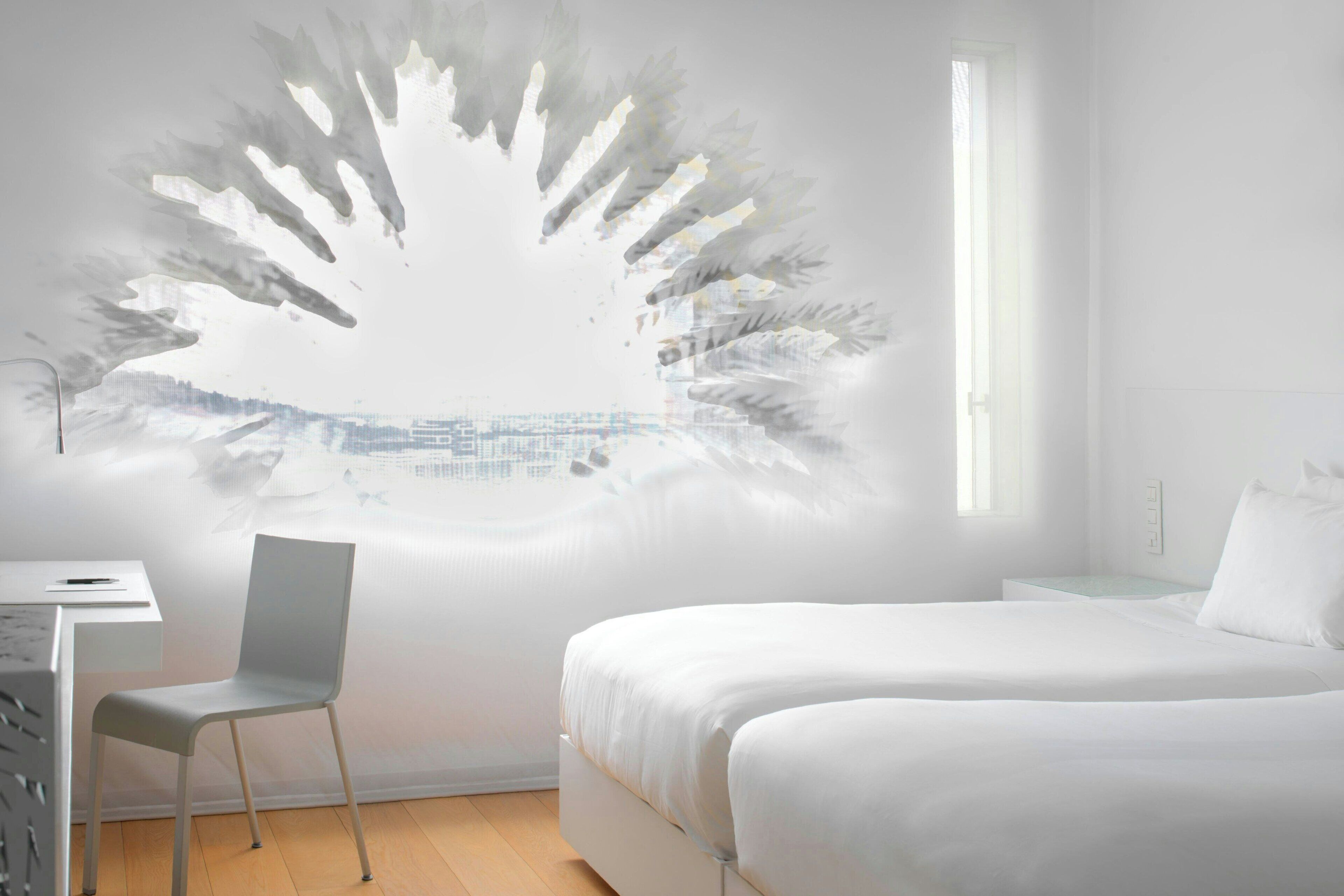 Un dormitorio minimalista con cama, una silla y una obra de arte en la pared.