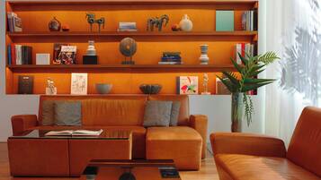 Una sala de estar moderna con un sofá de cuero, una mesa de centro y una estantería llena de libros y objetos decorativos.