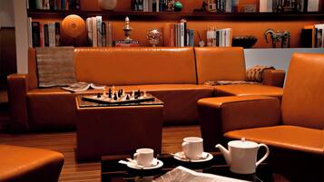 A cozy lounge area with leather sofas, a chessboard, cups, and a teapot on a table.