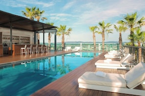 A rooftop pool area with lounge chairs, a bar, and palm trees. - Renaissance Barcelona Fira Hotel (L'Hospitalet de Llobregat)