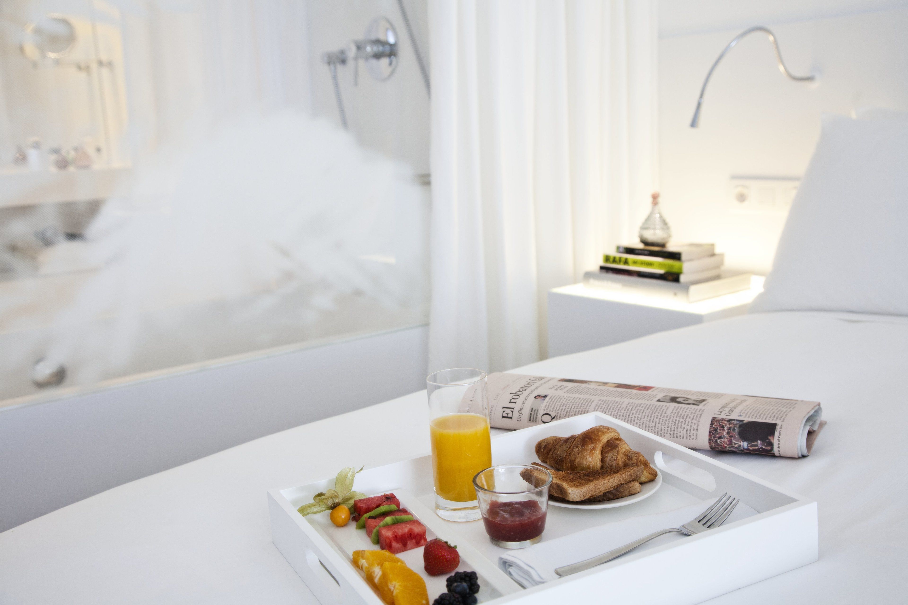 Ein Frühstücksbrett mit Toast, Obst und Saft auf einem weißen Tisch in einem Hotelzimmer.