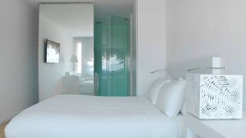 Une chambre d’hôtel moderne dotée d’un grand lit, d’une armoire à portes vitrées, d’une table de chevet agrémentée d’un objet décoratif et d’une lampe fixée au mur.