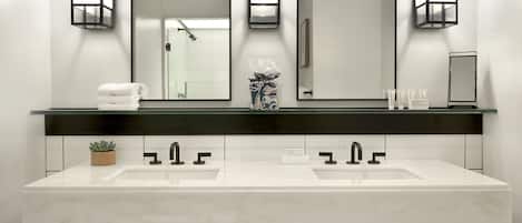 Un baño moderno con dos lavamanos, tres espejos y una encimera negra.