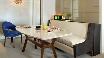 A modern dining area with a glass table, two chairs, a sofa, and a 'DO IT' sign on the wall.