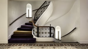A spiral staircase with a black metal railing and a white wall.
