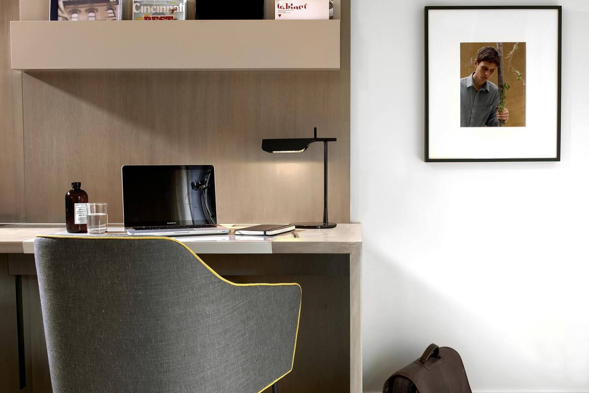 Un espacio de trabajo moderno con una computadora portátil, una lámpara de escritorio y una fotografía en el marco en la pared.