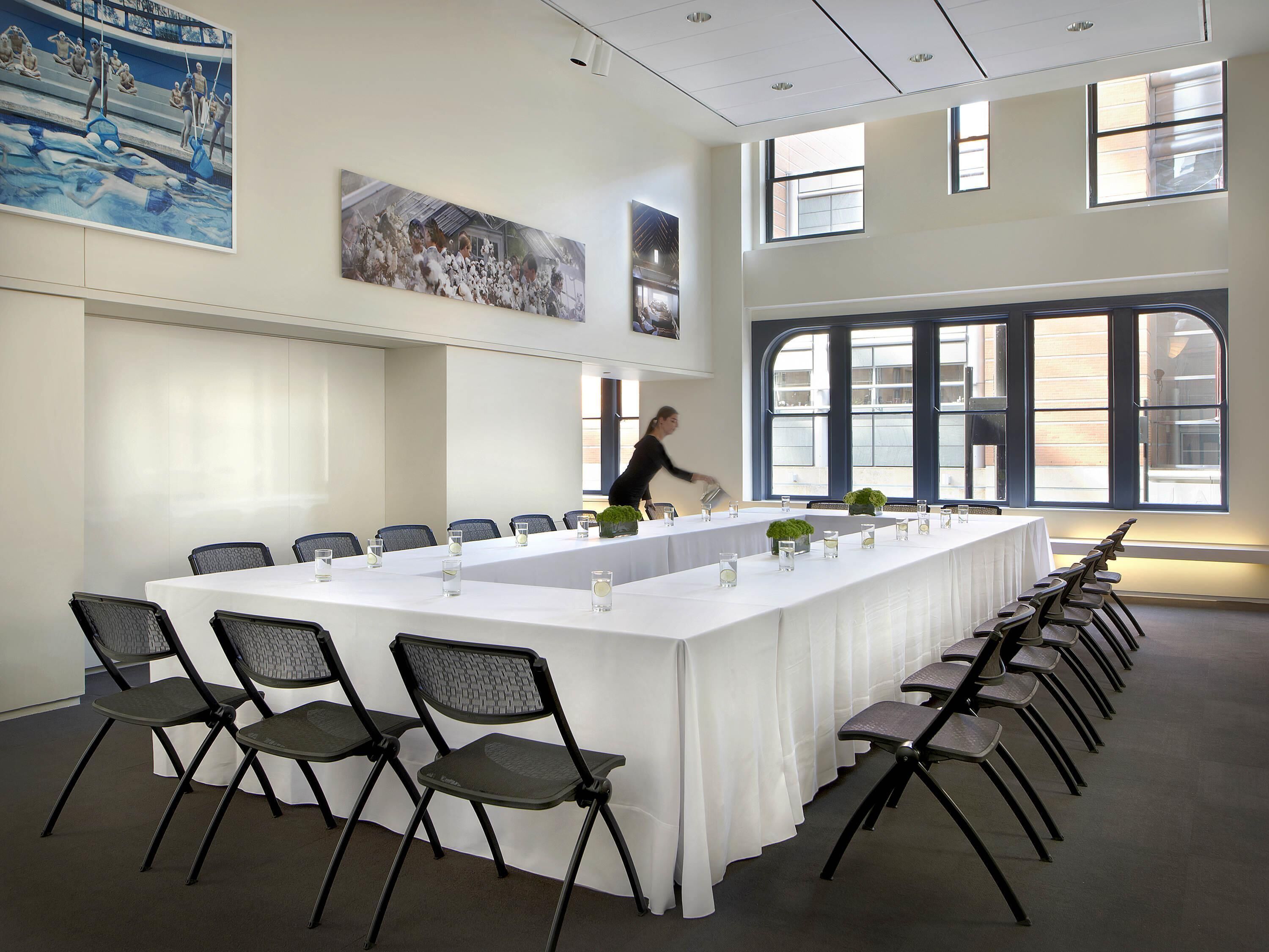 Une salle de conférence avec une longue table, des chaises et de grandes fenêtres.