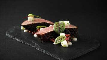 A black slate serving board with a piece of meat and garnishes.
