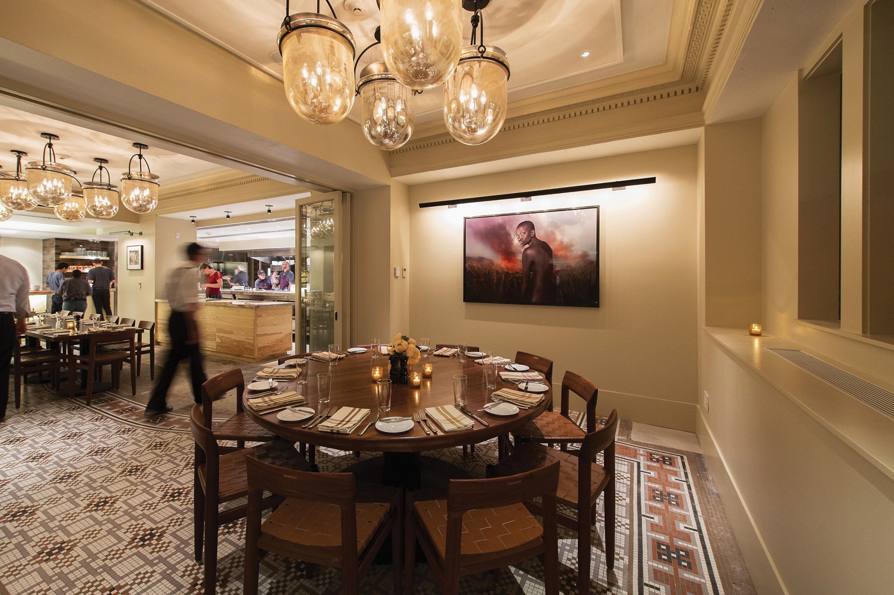 A formal dining room with a round table set for six, surrounded by wooden chairs.