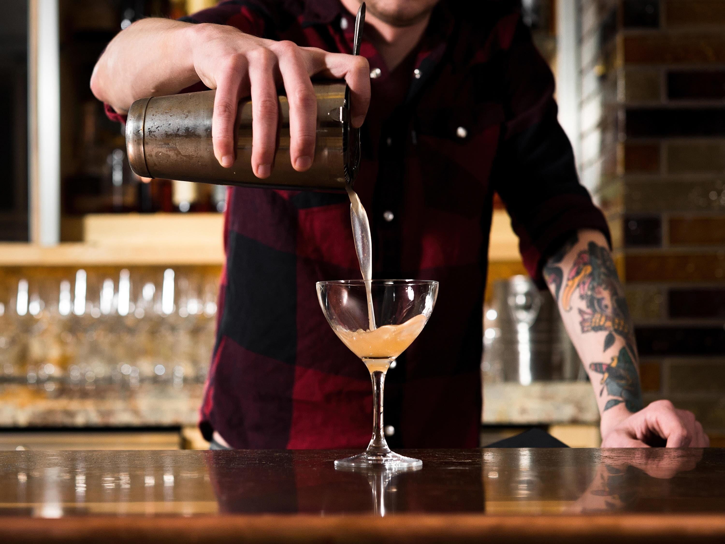 Eine Person gießt ein Getränk in ein Martini-Glas.