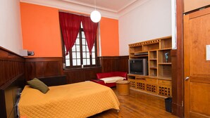 Ein Zimmer mit einem Bett, einem Fernseher und einem Holzschrank.