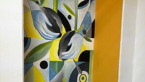 Ein Zimmer mit blauem Sessel, braunem Kissen und einem farbenfrohen abstrakten Gemälde an der Wand.