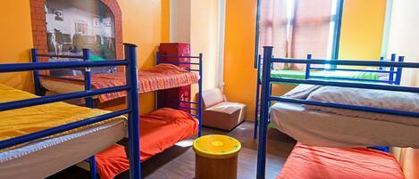A dormitory room with bunk beds, a small stool, and a brick fireplace.