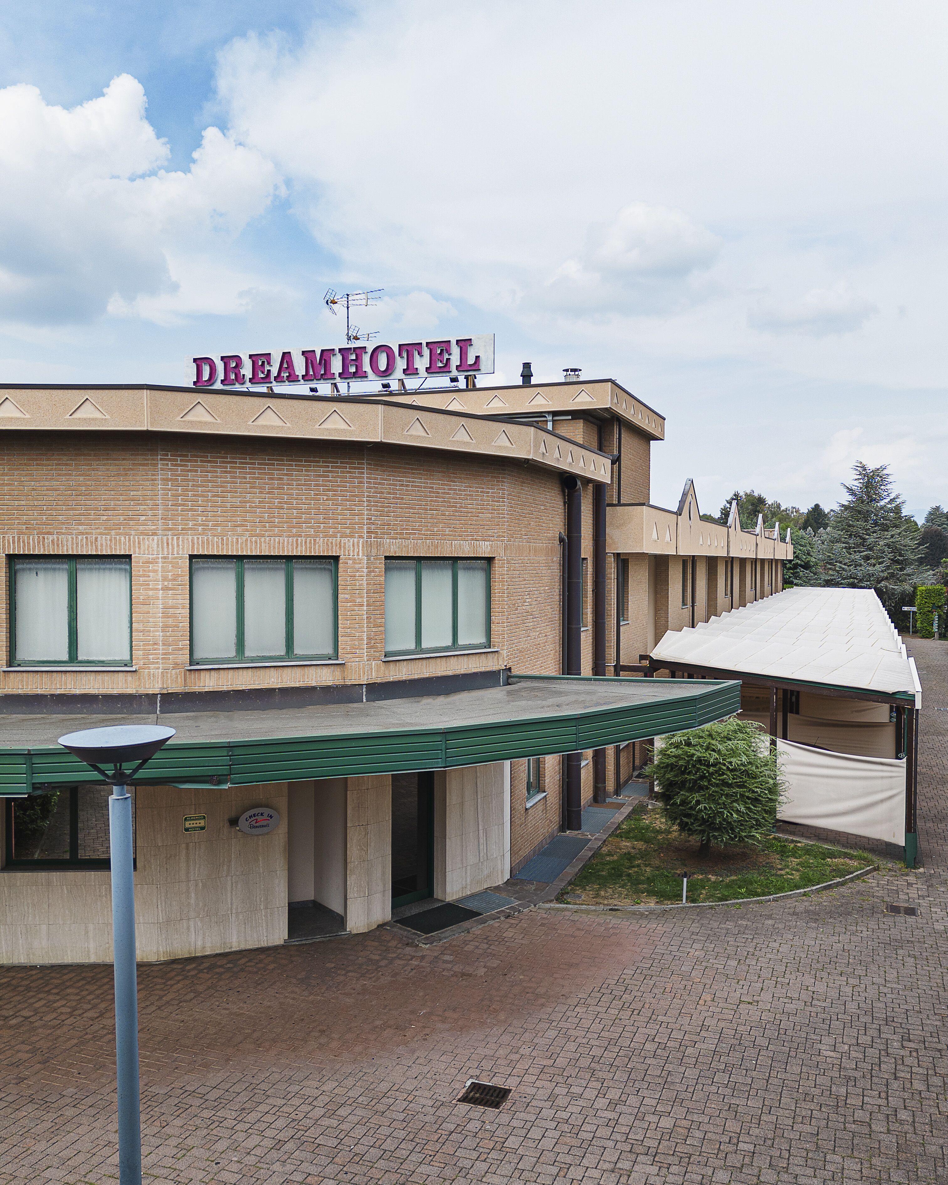 A brick building with a sign reading "DREAMHOTEL" and a covered entrance.