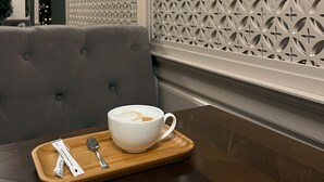 Un comedor con una bandeja de madera que contiene una taza de café, una cuchara y una servilleta.