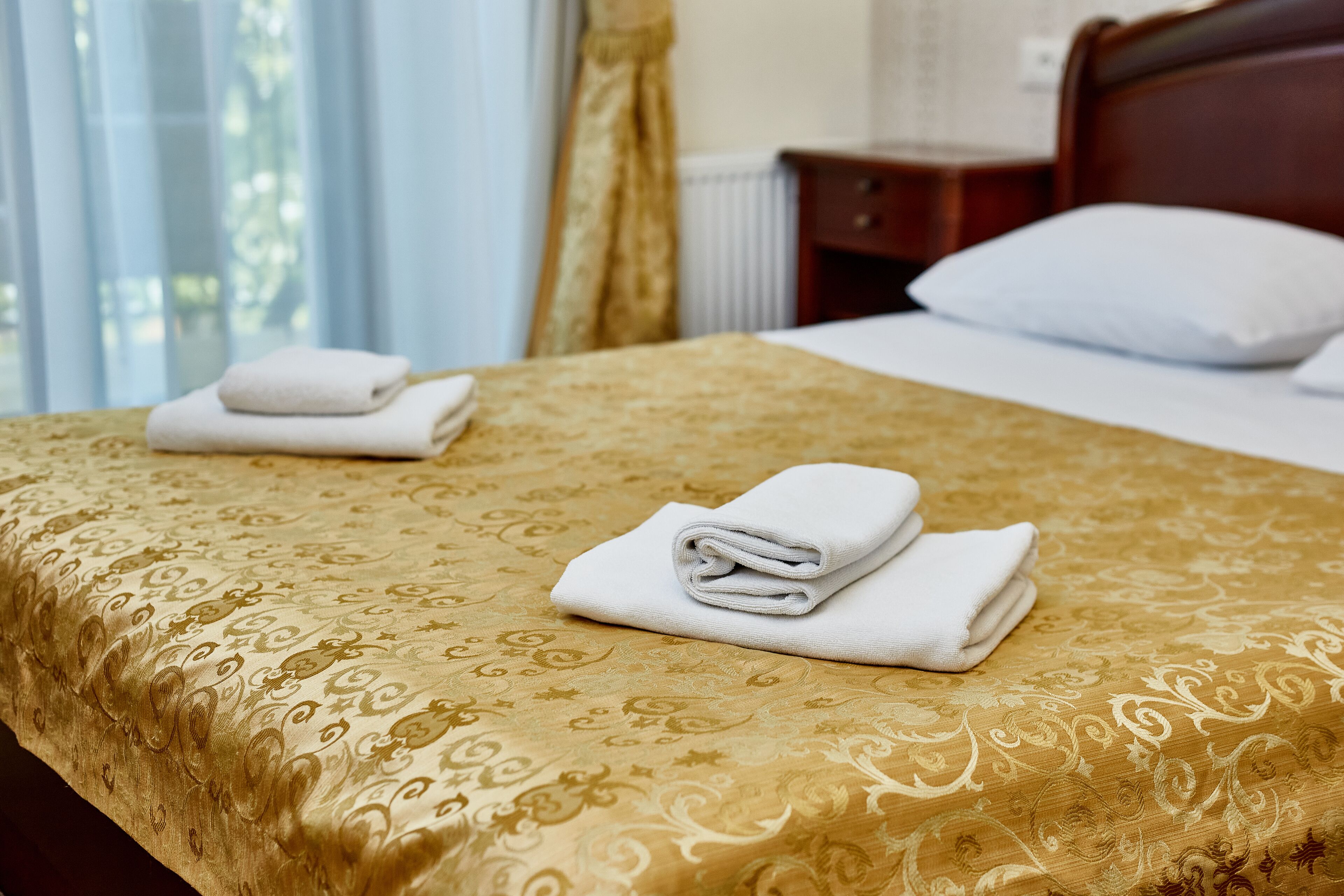A neatly made bed with a patterned bedspread and folded white towels.