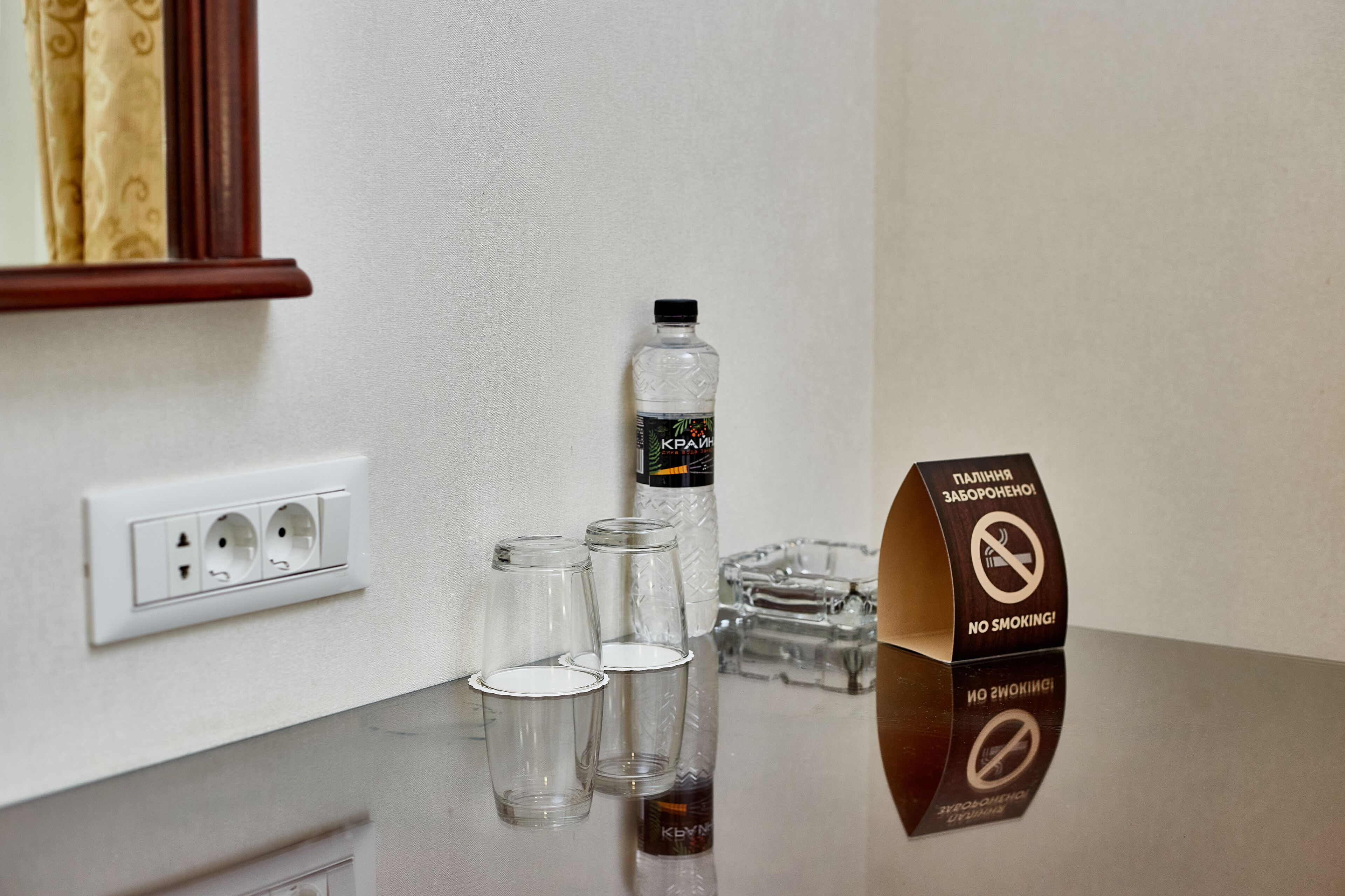 Ein Hotelrezeptionstresen mit einer Wasserflasche, Gläsern und einem Rauchverbotsschild.
