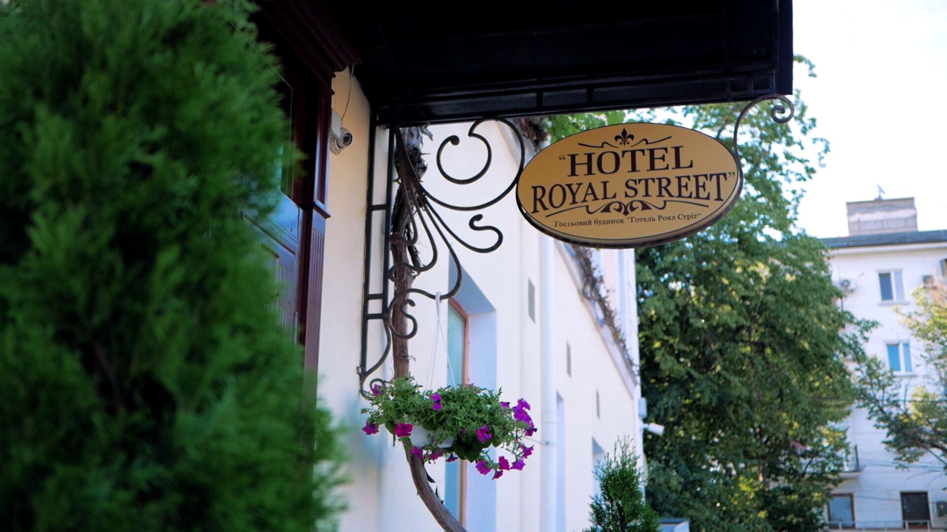 A hotel sign with the name "HOTEL ROYAL STREET" and a hanging flower basket.