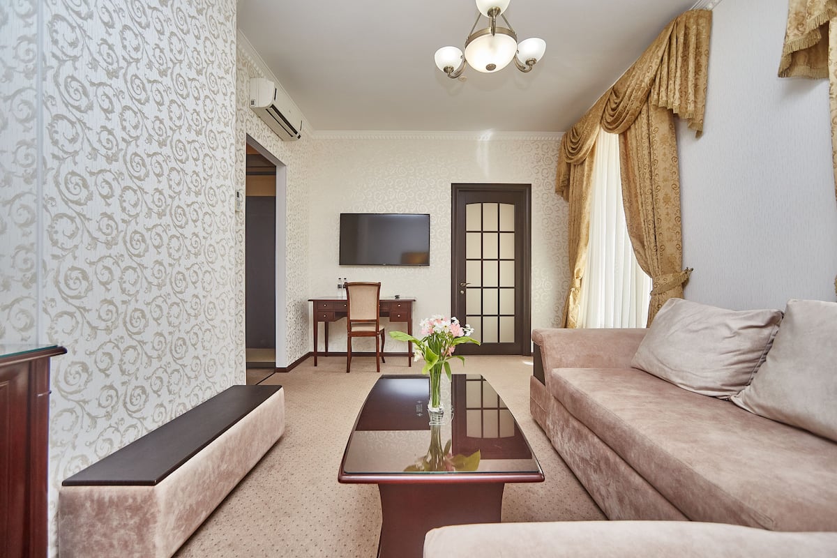 A living room with a sofa, a coffee table with a vase, a TV, and a door.