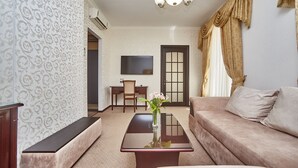 Una sala de estar con un sofá, una mesa de centro con un jarrón, un televisor y una puerta.
