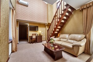 A living room with a sofa, coffee table, and a staircase. - Royal Street Hotel (Odesa)