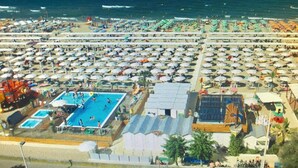 A crowded beach with numerous umbrellas and a large swimming pool. - Hotel Fantasy (Riccione)