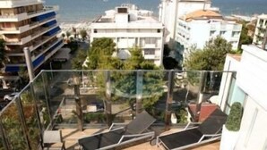 A rooftop terrace with a hot tub, lounge chairs, and a view of the sea and buildings. - Hotel Fantasy (Riccione)
