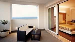 A balcony with a sofa, a small table, and a potted plant. - Hotel Fantasy (Riccione)