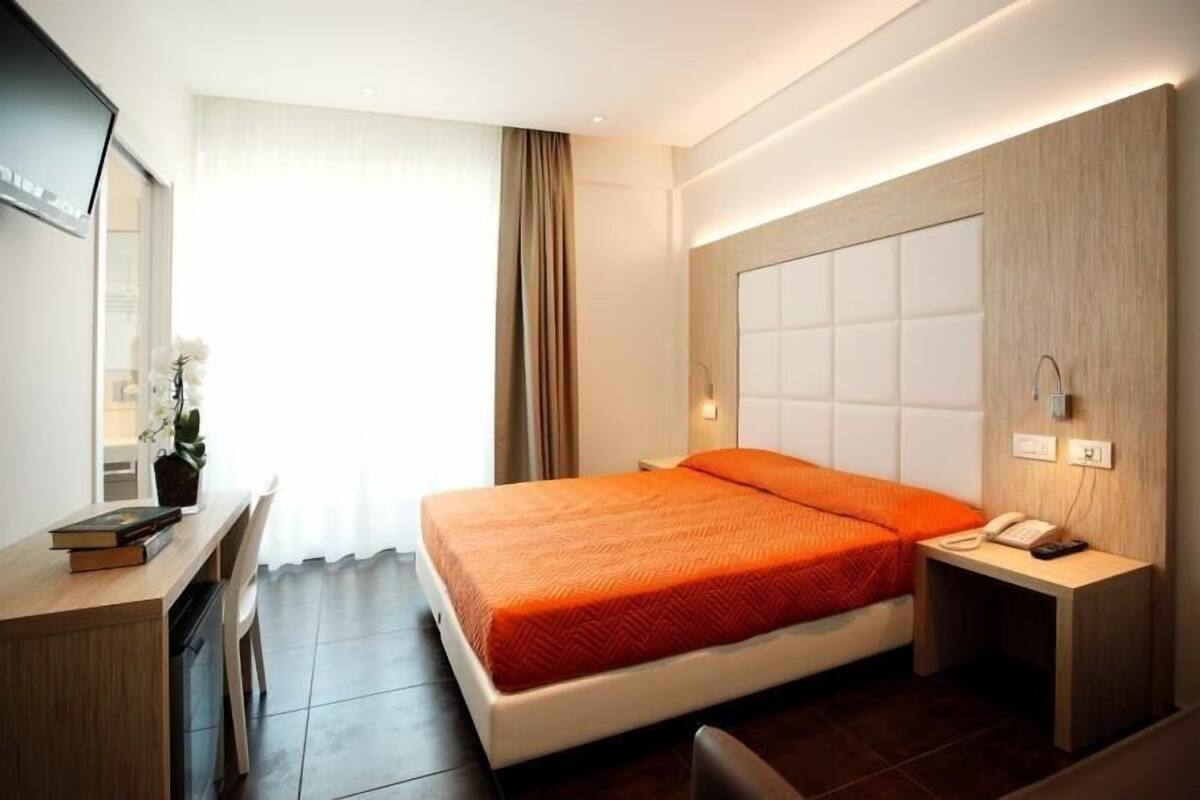 A modern hotel room with a large bed, a desk, and a television.