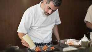 A chef in a white uniform preparing food at a counter with a focus on salmon and other ingredients. - TLV 88 Sea Hotel (Tel Aviv)