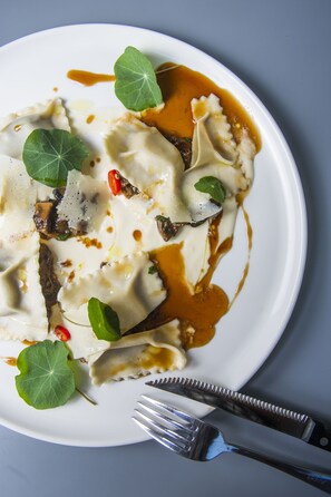 A plate of ravioli with sauce and garnishes. - TLV 88 Sea Hotel (Tel Aviv)