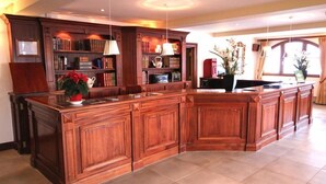 A spacious kitchen with a large island, wooden cabinetry, and a built-in bookshelf. - SportHotel Beausoleil (Huez)