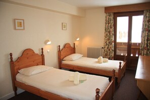 Ein Hotelzimmer mit zwei Holzbetten, einem Schreibtisch aus Holz und einem Heizkörper.